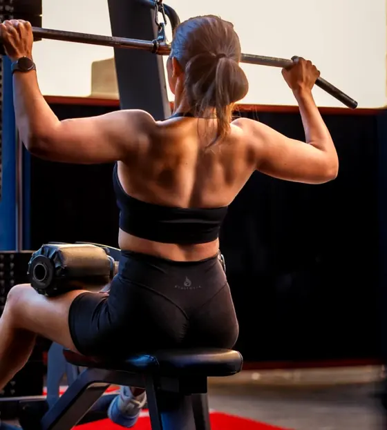 Rose from behind doing a lat pulldown, back muscles defined
