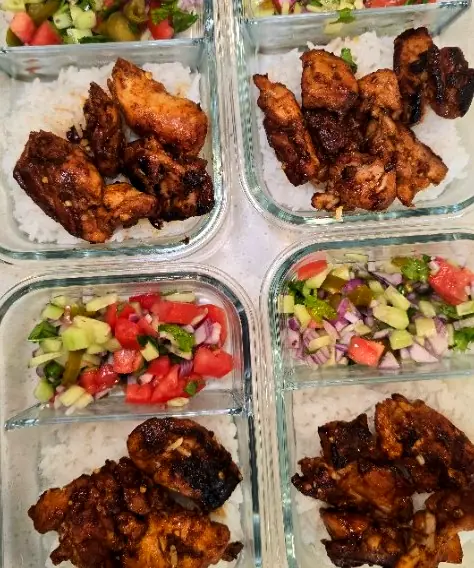 Four glass meal-prep boxes of charred chicken, rice and fresh salad