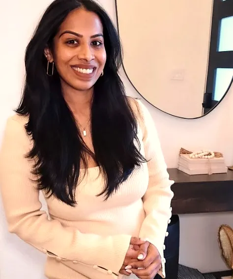 Rose smiling warmly in a cream knit dress