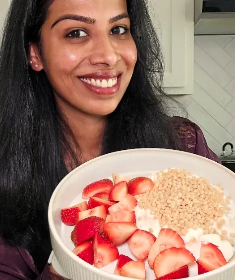 Rose smiling and holding a bowl of strawberries, Greek-style yogurt and soy protein crisps